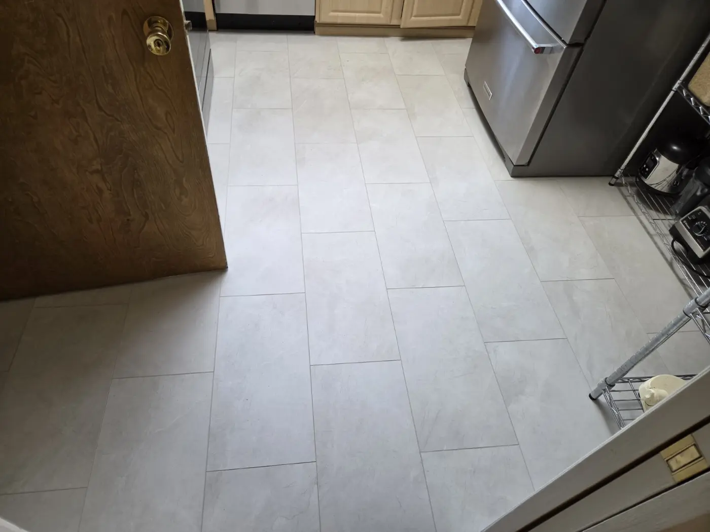 Completed light stone-look vinyl plank flooring in a residential kitchen