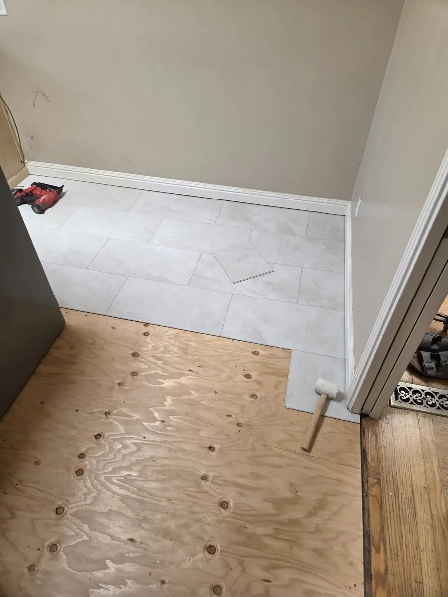 Light stone-look vinyl planks being installed across a prepared kitchen floor